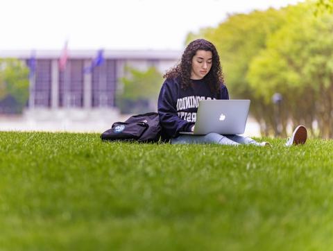 一名穿着ODU运动衫的女学生正在考夫曼商城学习，她的笔记本电脑放在腿上